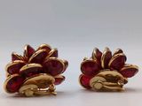 a pair of red and gold earrings on a white surface
