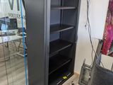 une bibliothèque noire avec une porte vitrée dans une pièce