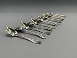 six spoons are lined up in a row on a gray surface
