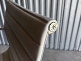 a white chair with a button on it in front of a metal wall