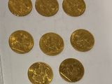 several gold coins sitting on top of a piece of paper on a table