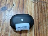 a small black object on a wooden table with a paper roll
