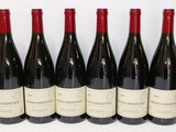 six bottles of red wine lined up in a row on a white surface