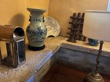 a table with a lamp, a vase, and other items on it