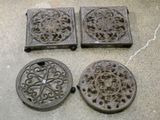 quatre grilles de cheminée anciennes en fonte posées sur un sol en béton