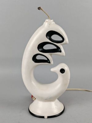 une lampe blanche surmontée d'un oiseau noir et blanc