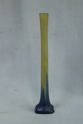 un vase bleu et jaune posé sur une surface blanche