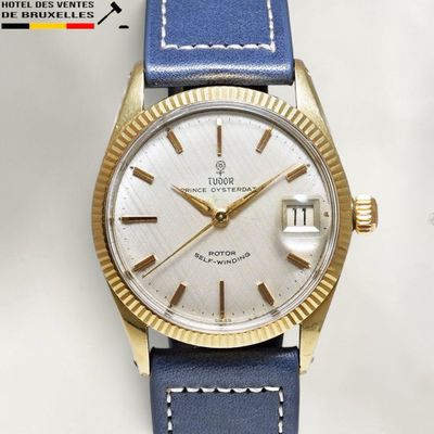 une image représentant une montre dorée et bleue avec un cadran blanc