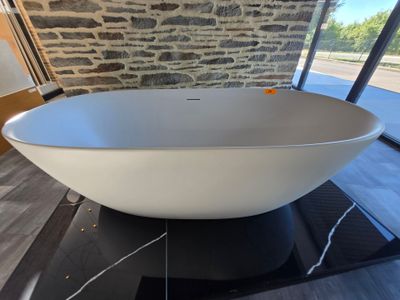 une grande baignoire blanche posée sur un tapis noir