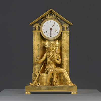 une horloge en or sur laquelle est représentée la statue d'une femme