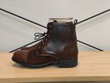 quelqu'un porte une paire de bottes marron posée sur une étagère en bois