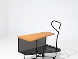 une image représentant une petite charrette noire sur laquelle est posée une table en bois