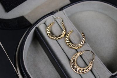 two pairs of gold hoop earrings in a case