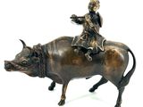 bronze figurine of a boy riding a bull with a bird on its back