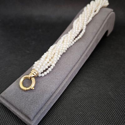 Gros plan sur un collier de perles blanches avec un fermoir en or