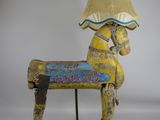 une image représentant un cheval de bois sur la tête duquel est posée une lampe