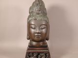 tête en bronze d'une statue de Bouddha posée sur un socle en bois