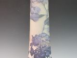 un vase avec des fleurs peintes dessus, posé sur une table
