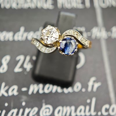 un gros plan d'une bague sertie de diamants et de saphirs, photographiée avec un téléphone portable