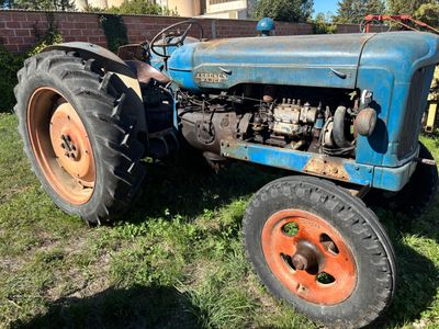 un tracteur bleu qui est garé dans l'herbe
