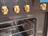 a black oven with four brass knobs on the front of it