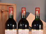 three bottles of red wine sitting on a table next to a wooden box