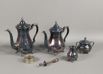 a silver tea set on a table with a cup and spoon