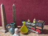 une petite statue représentant un bébé assis sur une table, à côté d'un petit train miniature