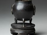 un pot noir posé sur un socle en bois