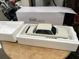 a white toy car in a white box on a table