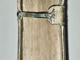 someone is holding a book with a metal handle in their hand