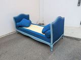 a blue day bed with pillows on it in a corner