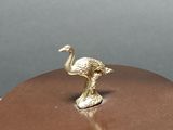 brass figurine of an ostrich on top of a brown plate