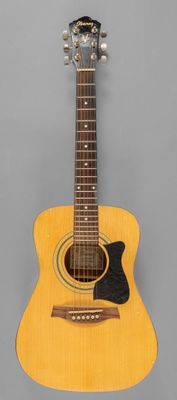 un gros plan d'une guitare acoustique sur fond gris