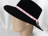 a black hat with a pink ribbon around the brim