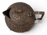 an old metal teapot with a lid on a white surface