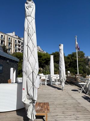 tables and umbrellas on a wooden deck with a building in the background