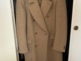 beige wool coat hanging on a hanger in a closet