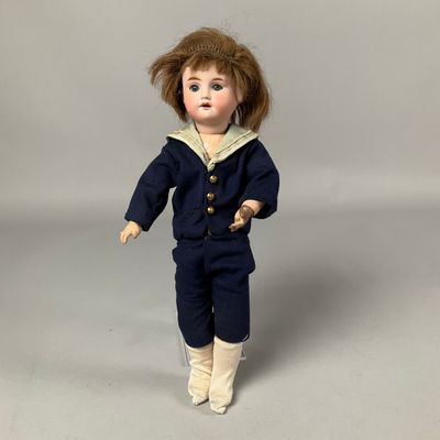 une image représentant une poupée représentant un petit garçon en costume de marin