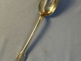 silver plated spoon on a white tablecloth with a shadow on the surface