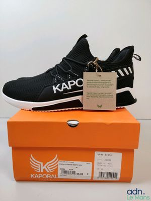 Les baskets noires et blanches sont posées sur une boîte orange.
