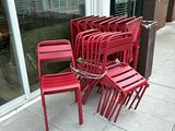 de nombreuses chaises rouges alignées sur le trottoir devant un immeuble
