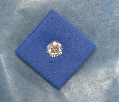 un gros plan d'un diamant dans une boîte bleue posée sur un tissu bleu
