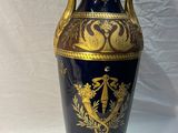 un vase bleu orné de motifs dorés, posé sur une table