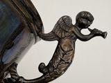 a silver vase with an angel on it on a table