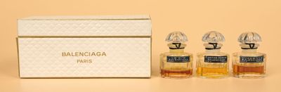 three small bottles of perfume sitting next to a box on a table