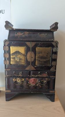 une petite commode posée sur une table à côté d'un livre