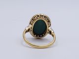 a close up of a ring with a green stone in it