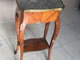 une petite table en bois avec un plateau en marbre, posée sur un sol carrelé