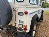 a white truck with a black tire cover parked in the grass